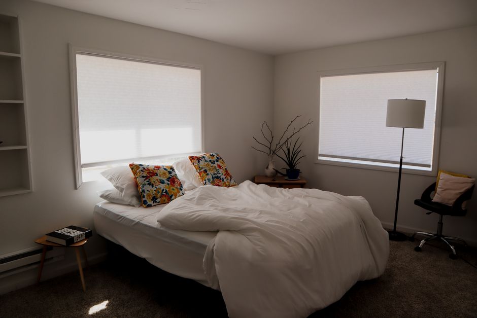 Elegant bedroom window showing soft custom shades and drapes